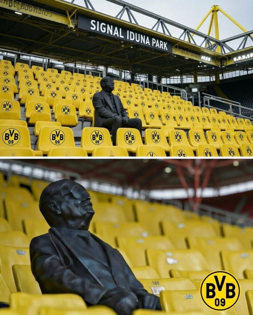 Im ikonischen Signal Iduna Park, der Heimat von Borussia Dortmund, erzählt eine stille Gestalt auf der Tribüne eine Geschichte, die Herzen erschüttert 😢🖤 Eine Statue eines treuen Fans bewacht nun seinen lebenslangen Stammplatz. Blindheit raubte ihm das Augenlicht, aber nie seine Leidenschaft ⚽🔥 Geführt von der Stimme seines Sohnes „sah“ er jeden Pass, jeden Jubel, jedes Tor. Heute hält Bronze seinen Platz — sein Geist donnert lauter als die Menge 💔🏟️ Wahre Legenden spielen nicht nur… sie leben für immer.